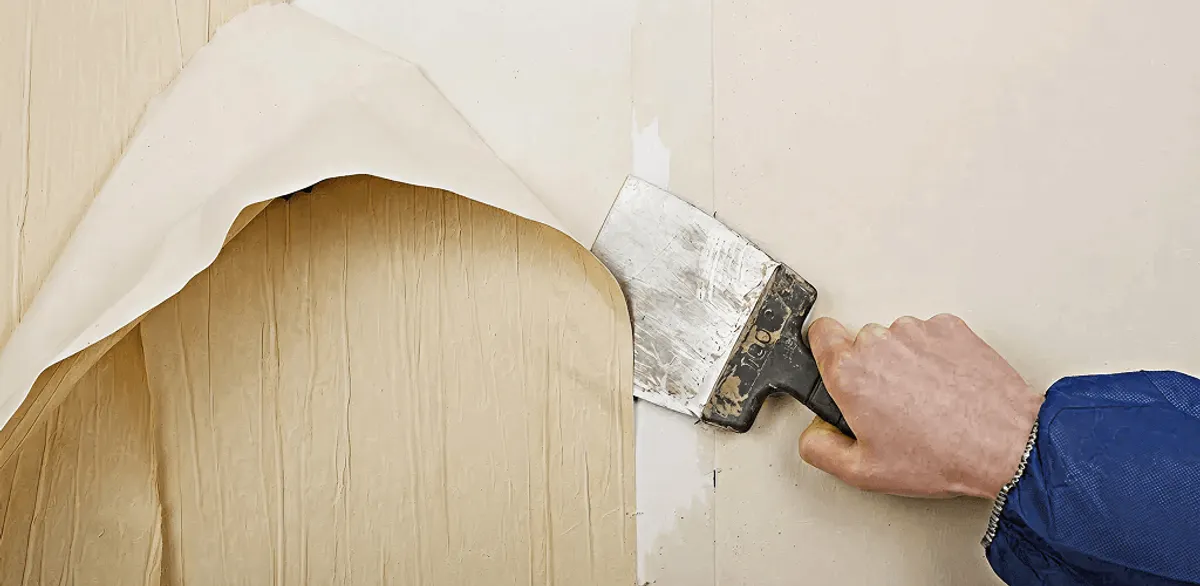 Handyman removing wallpaper with a scraper for wall preparation in South Bend, IN