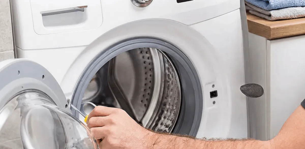 Handyman repairing a front-load washing machine and inspecting the drum in South Bend, IN